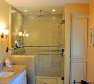 Ein helles Bad bei dem die Dusche mit einer Duschtrennwand aus Glas abgetrennt ist.