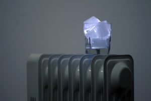 Ein Glas mit leuchtenden Eiswürfeln steht auf einer Heizung.